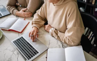 picture of two people with notebooks and at a laptop making a decision on whether to chose an upfront website or pay monthly website