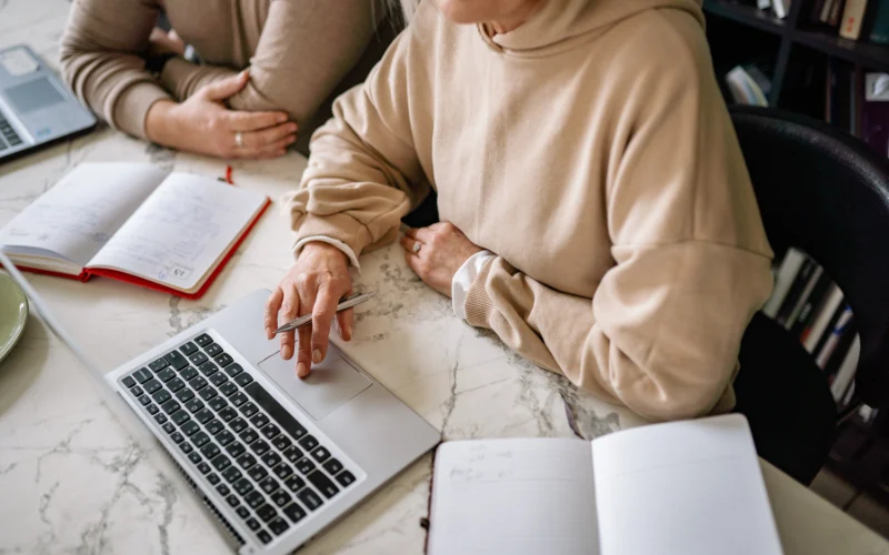 picture of two people with notebooks and at a laptop making a decision on whether to chose an upfront website or pay monthly website